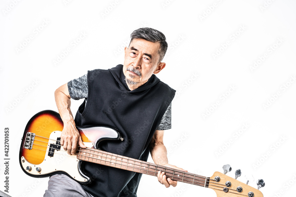 A funny Asian elder cool man has fashion in gray t-shirt And black vest play bass guitar. Shoot On white background in the studio. Positive active old cool senior healthy retirement concept