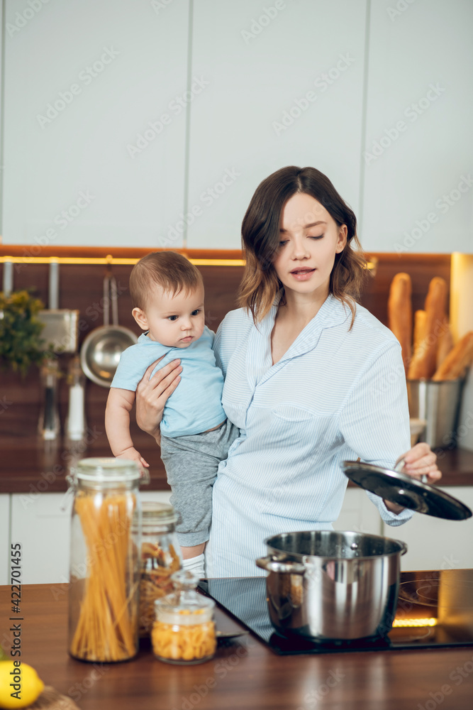 Mom with child looking into saucepan on stove Mom with child looking into saucepan on stove