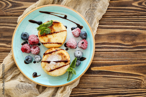 Sweet cheese pancakes with berries and mint leafs on wooden table