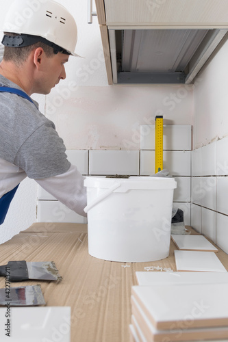 the tile installation wizard measures the correct laying of white tiles, using the yellow level