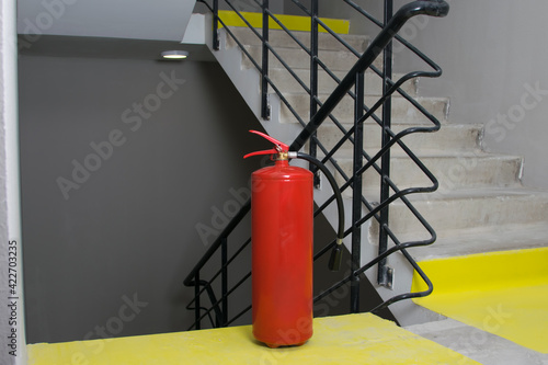 a red large fire extinguisher stands on the landing of the stairwell for safe evacuation in case of fire © kurgu128