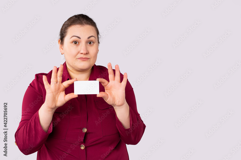 Your message may be here. Pretty young excited overweight woman is holding a blank board, showing blank business card. Studio portrait on grey background. Your message may be here. Pretty young excited overweight woman is holding a blank board, showing blank business card. Studio portrait on grey background.