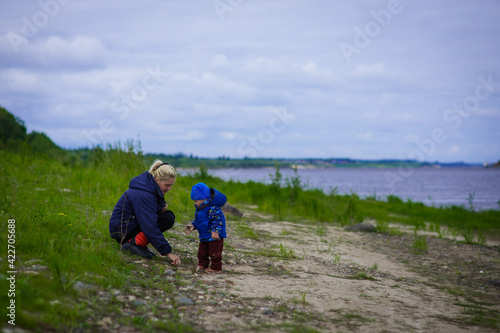 portrait of a boy in a blue jacket with his mother in the open air, river bank, selective focus