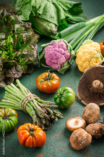 Assortment of organic vegetables and edible mushrooms on green background