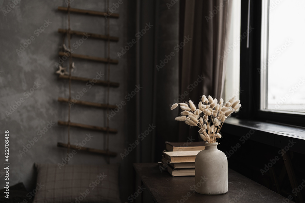 Rabbit bunny tail grass bouquet in pot, books stack on table against window Rabbit bunny tail grass bouquet in pot, books stack on table against window