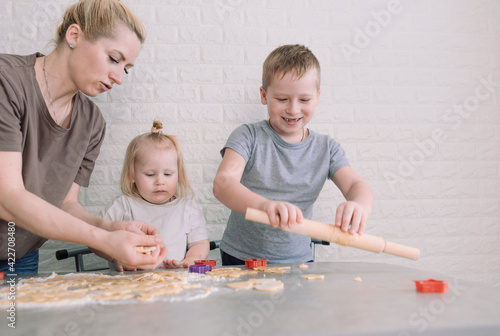 kids help their mom to make delicious cookies at home in the kitchen. joint cooking is a concept of family happiness
