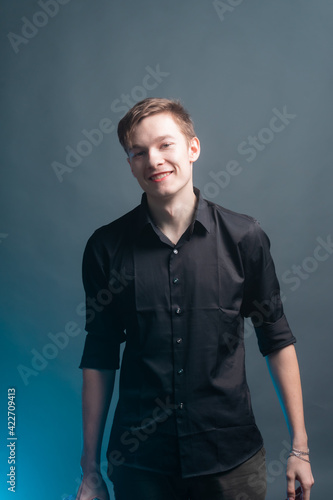 Young guy goes on a gray background with a bottle of alcohol