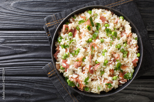 Arborio rice with green peas and prosciutto Italian risotto close-up in a plate on the table. horizontal top view above photo