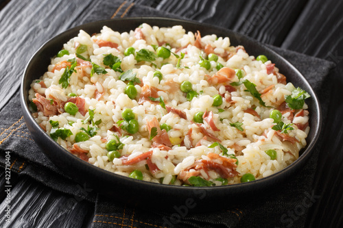 Arborio rice with green peas and prosciutto Italian risotto close-up in a plate on the table. horizontal