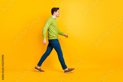 Full length body size profile side view of content cheerful guy it specialist geek walking isolated over bright yellow color background