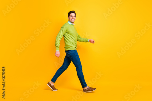 Full length body size profile side view of attractive content cheerful guy executive manager walking isolated over bright yellow color background