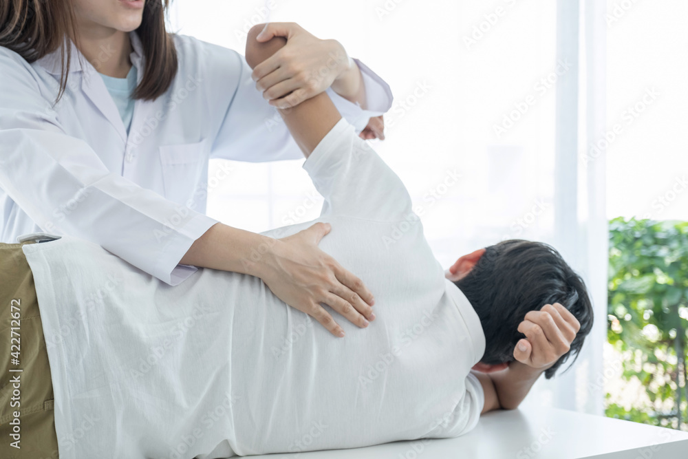 Naklejka premium Female hands doctor doing physical therapy By extending the back of a male patient