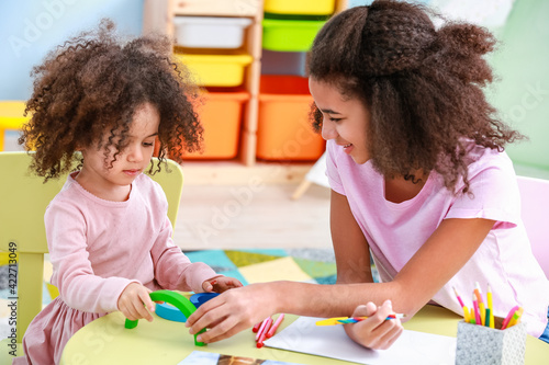 Cute African-American sisters drawing at home