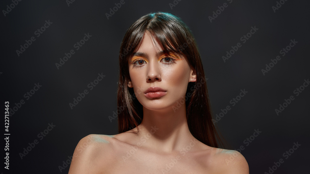 Portrait of naked young brunette woman with big brown eyes and colorful makeup posing for camera isolated over black background Portrait of naked young brunette woman with big brown eyes and colorful makeup posing for camera isolated over black background