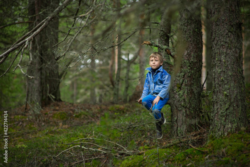 a 7-9-year-old boy in a blue denim jacket walks in the summer forest, selective focus