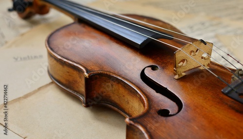 An old antique violin on a table with yellowed sheet music close-up.