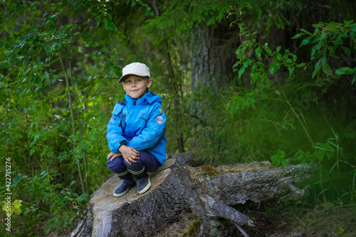 a boy in a blue jacket and cap in the woods in summer, selective focus © Ekaterina