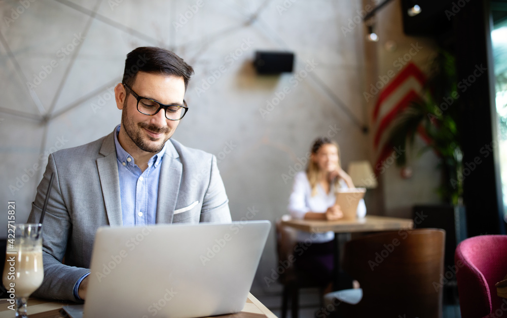 Happy confident businessman working, using laptop in office