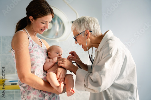 Happy pediatrician doctor with baby checking possible heart defect