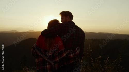 Hikers enjoying sunset in mountains. Romantic couple hugging together outdoor