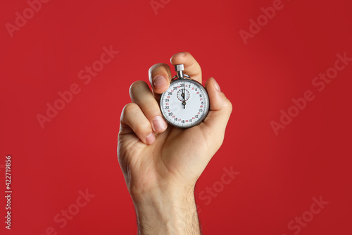 Man holding vintage timer on red background, closeup photo