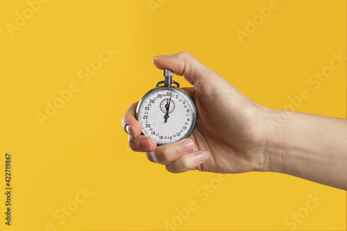 Woman holding vintage timer on yellow background, closeup photo