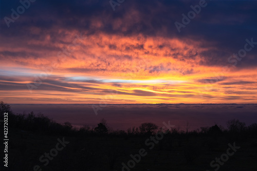 Amazingly beautiful sunrise over sea. breathtaking colors in sky from rising sun. Silhouette of coast against background of glowing clouds © Biskariot