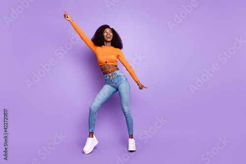 Photo of cute charming dark skin woman dressed orange crop top dancing isolated purple color background