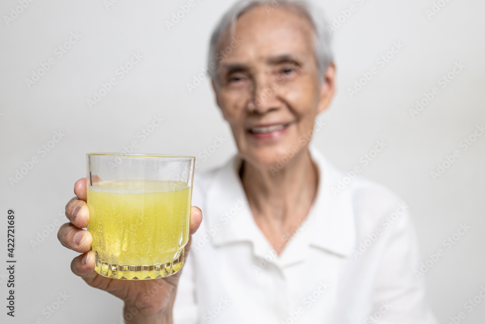 Healthy asian senior grandmother drinking a glass of vitamin C or orange juice,elderly people with effervescent vitamin C,strengthening the immunity for cold,flu,fight against the Coronavirus,COVID-19 Healthy asian senior grandmother drinking a glass of vitamin C or orange juice,elderly people with effervescent vitamin C,strengthening the immunity for cold,flu,fight against the Coronavirus,COVID-19