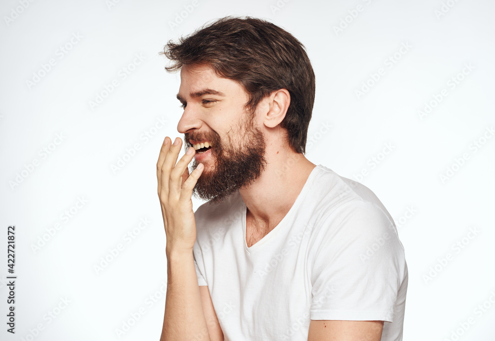 Emotional man with a beard holds his hands near his face on a light background cropped view Emotional man with a beard holds his hands near his face on a light background cropped view