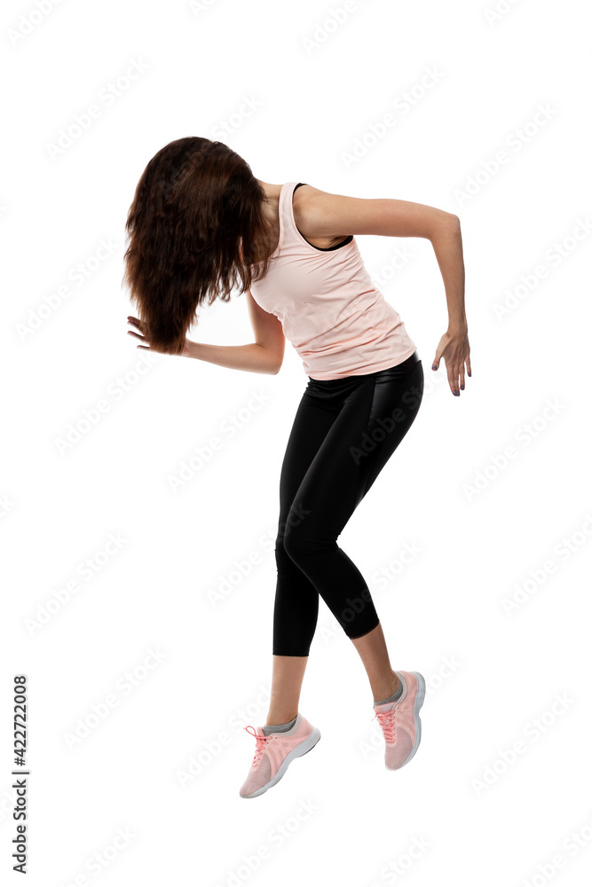 Young woman in sportswear is jumping. Brunette with loose hair. Activity and movement. Isolated on white background. Vertical. Full height. Young woman in sportswear is jumping. Brunette with loose hair. Activity and movement. Isolated on white background. Vertical. Full height.