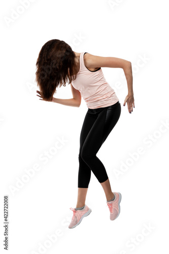 Young woman in sportswear is jumping. Brunette with loose hair. Activity and movement. Isolated on white background. Vertical. Full height. © Анна Демидова
