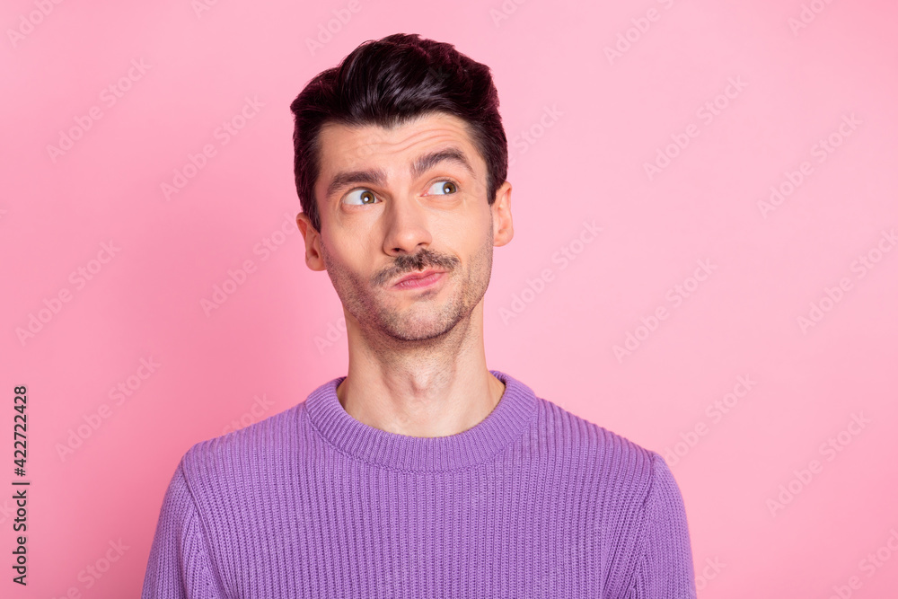Photo of funny thoughtful young man dressed purple pullover looking empty space isolated pink color background Photo of funny thoughtful young man dressed purple pullover looking empty space isolated pink color background