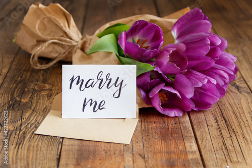 Bouquet and MARRY ME card on wooden table