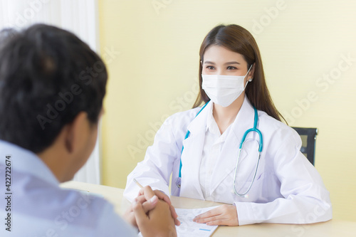 Asian female doctor asking patient questions by wearing a surgical mask at all times in health care,pollution PM2.5 and new normal concept.