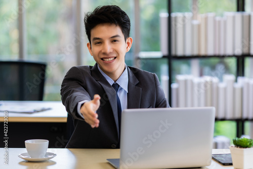 Friendly Asian businessman offering hand to camera