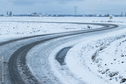 Snow-covered road going through the fields