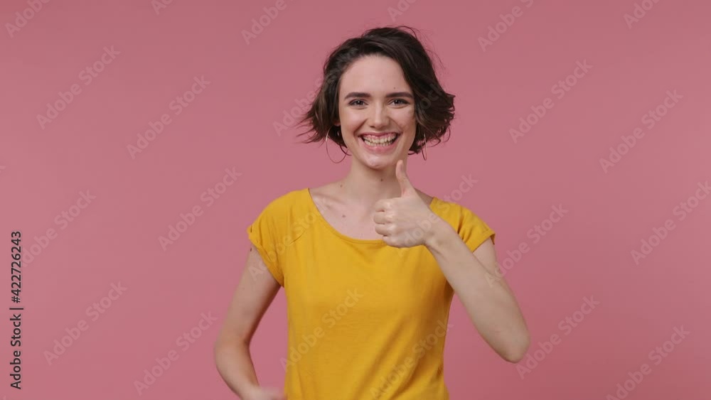 Back rear view brunette short hairdo young woman 20s in basic casual yellow t-shirt turn around camera showing thumbs up like gesture isolated on pastel pink background studio People lifestyle concept Back rear view brunette short hairdo young woman 20s in basic casual yellow t-shirt turn around camera showing thumbs up like gesture isolated on pastel pink background studio People lifestyle concept