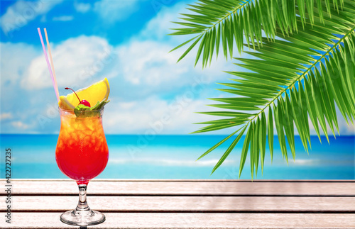 fresh summer cocktail on the sea in the shade of palm leaves, free space for text