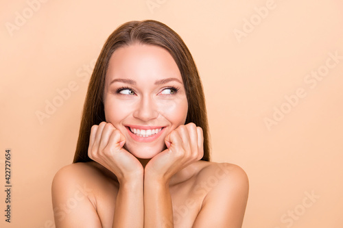 Portrait of pretty curious cheerful girl pure soft skin looking aside copy space isolated over beige pastel color background