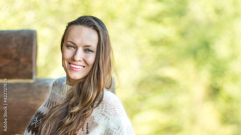 Positive nice young woman smiling while standing on a wooden terrace and breathing fresh air Positive nice young woman smiling while standing on a wooden terrace and breathing fresh air