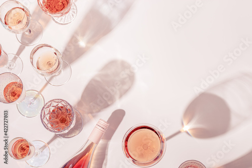 Fototapeta Naklejka Na Ścianę i Meble -  Rose wine assortment in crystal glasses, bottle of rose champagne sparkling wine with daylight and shadows.