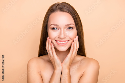 Portrait of pretty cheerful girl touching soft shine skin domestic procedure isolated over beige pastel color background