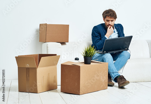 Manager sits on the couch with a laptop working professional boxes with things