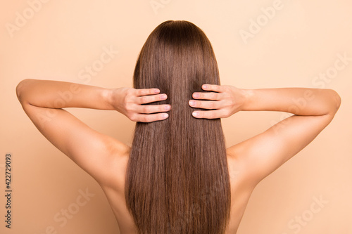 Rear photo of young person arms touch perfect healthy long hair wear nothing isolated on beige color background