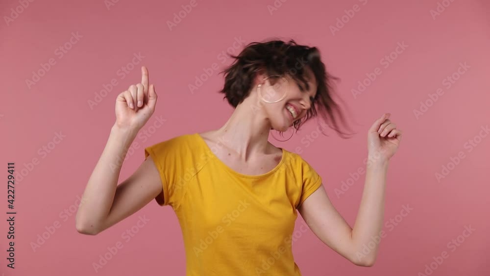 Short hairdo young woman 20s in yellow t-shirt dance clenching fists waving rising expressive gesticulate hands fool around have fun celebrate play fluttering hair isolated on pastel pink background Short hairdo young woman 20s in yellow t-shirt dance clenching fists waving rising expressive gesticulate hands fool around have fun celebrate play fluttering hair isolated on pastel pink background