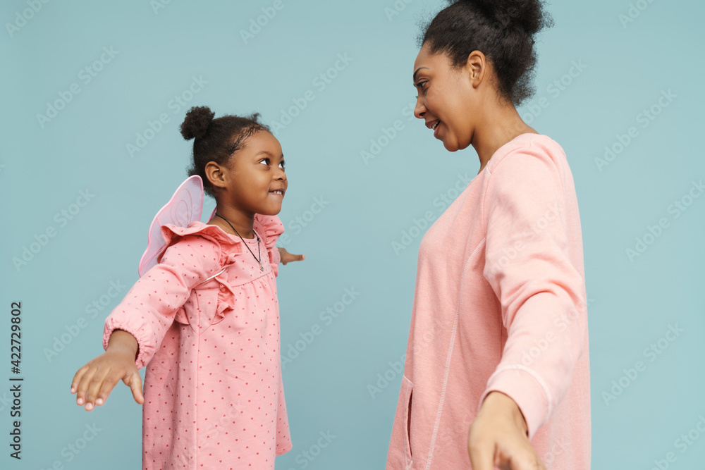 Happy black mother and daughter with butterfly wings making fun together Happy black mother and daughter with butterfly wings making fun together