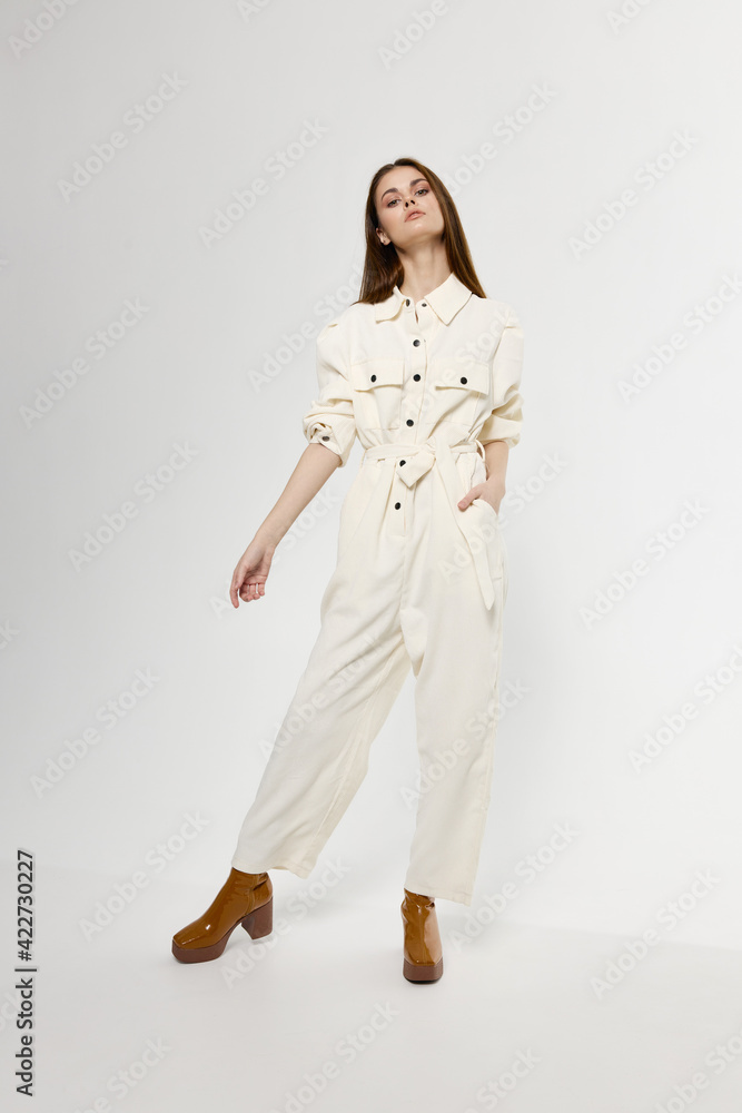 a pretty woman in a jumpsuit gesturing with her hands on a light background in full growth a pretty woman in a jumpsuit gesturing with her hands on a light background in full growth