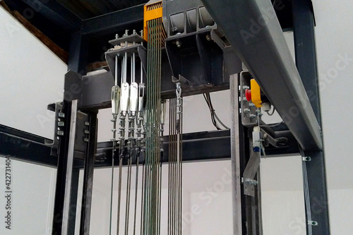 An electric motor and steel cables are seated in the passenger elevator shaft in an office building.