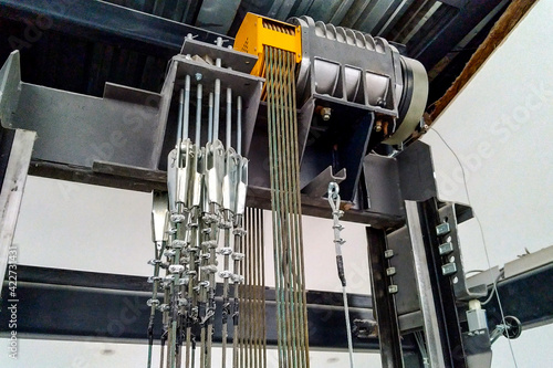 An electric motor and steel cables are seated in the passenger elevator shaft in an office building.